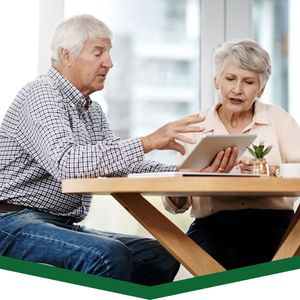 elderly couple looking at tablet making financial decisions at kitchen table