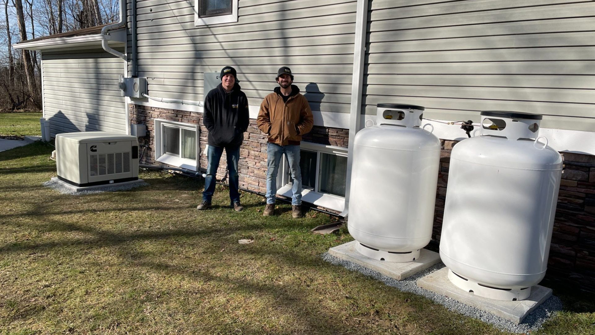 Two generator technicians standing next to home generator