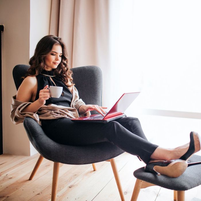 comfy lounging on chair in living room or bedroom, with laptop and tea and heels