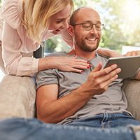 couple smiling looking at tablet