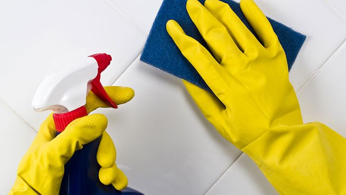 scrubbing tile surface spray bottle yellow gloves