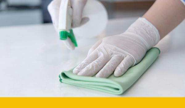 cleaning person wiping surface with spray bottle and towel