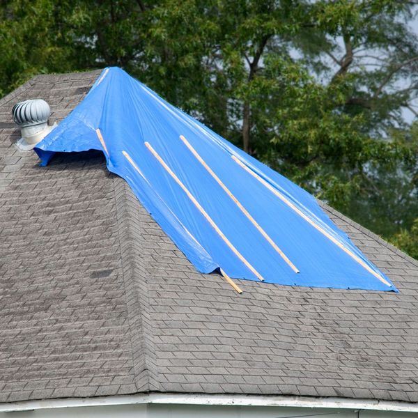 a blue tarp on a old, sagging roof