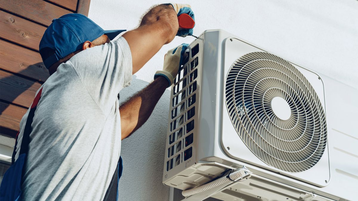 AC technician repairing an outdoor condenser unit on a home in Lauderhill, FL