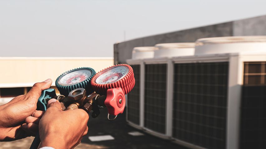 Professional HVAC technician checking refrigerant pressure gauges during preventive AC maintenance service on commercial air conditioning systems. Image for article about why HVAC maintenance is important, including AC maintenance in Pompano Beach and Lauderhill. HVAC technician performing preventive AC maintenance on rooftop air conditioning units in South Florida