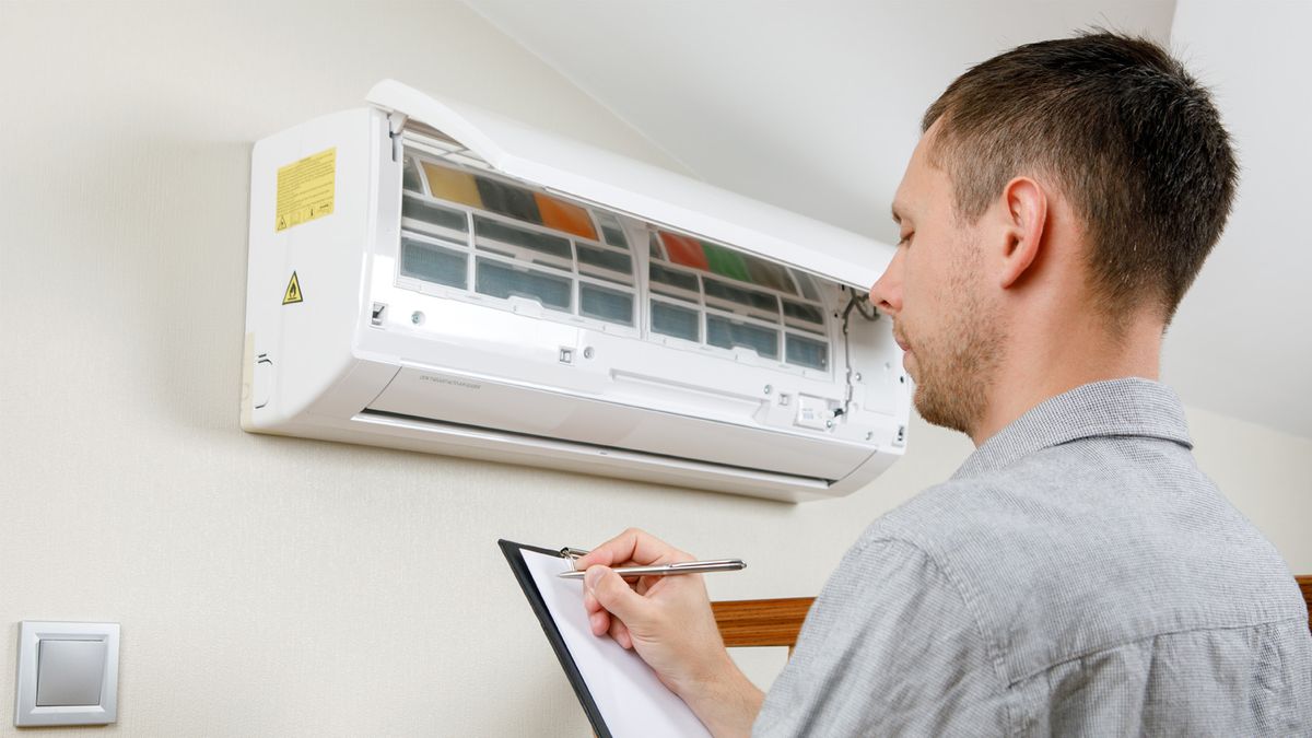 HVAC technician inspecting an AC unit during a load assessment