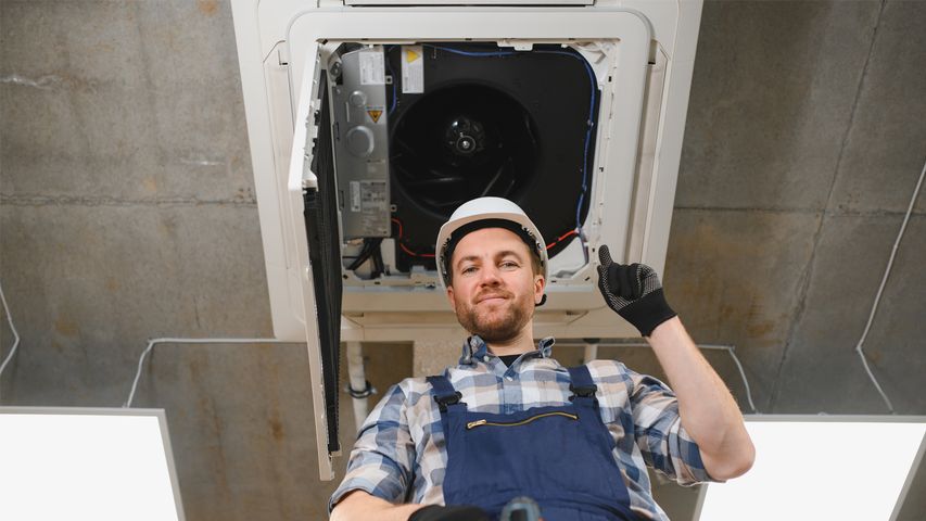 technician performing preventative HVAC maintenance inspecting ceiling air conditioning unit for routine service in Florida
