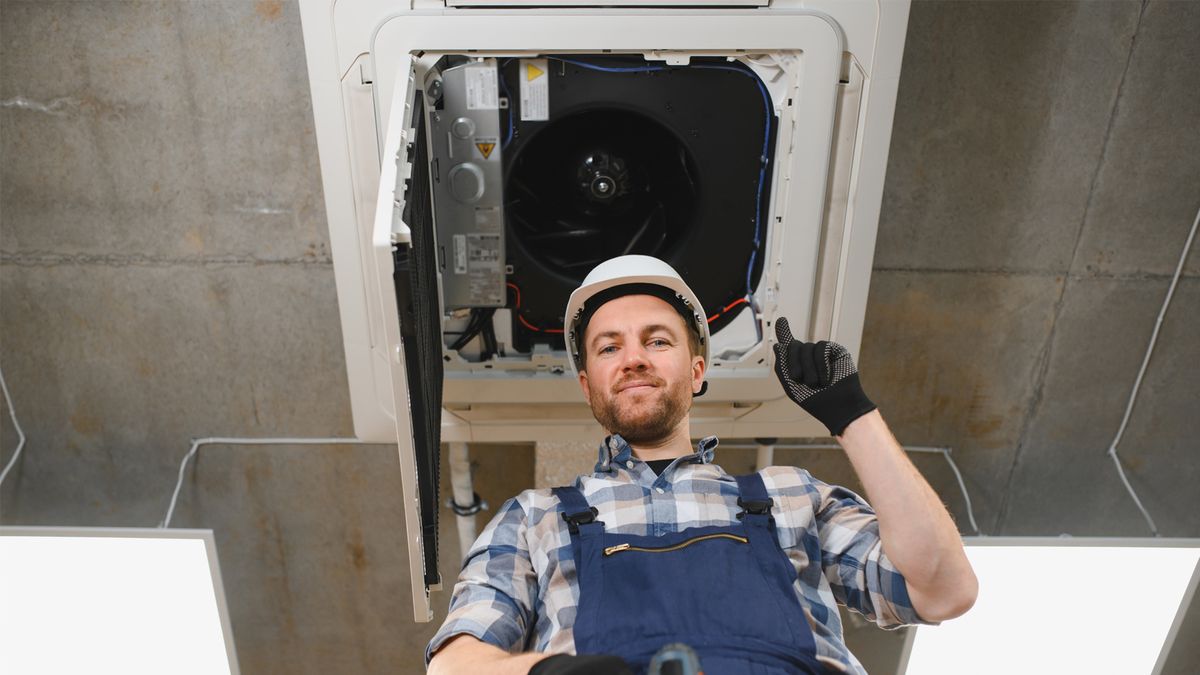 technician performing preventative HVAC maintenance inspecting ceiling air conditioning unit for routine service in Florida