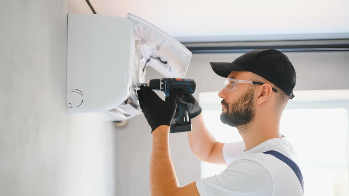 Technician installing a ductless mini-split indoor unit