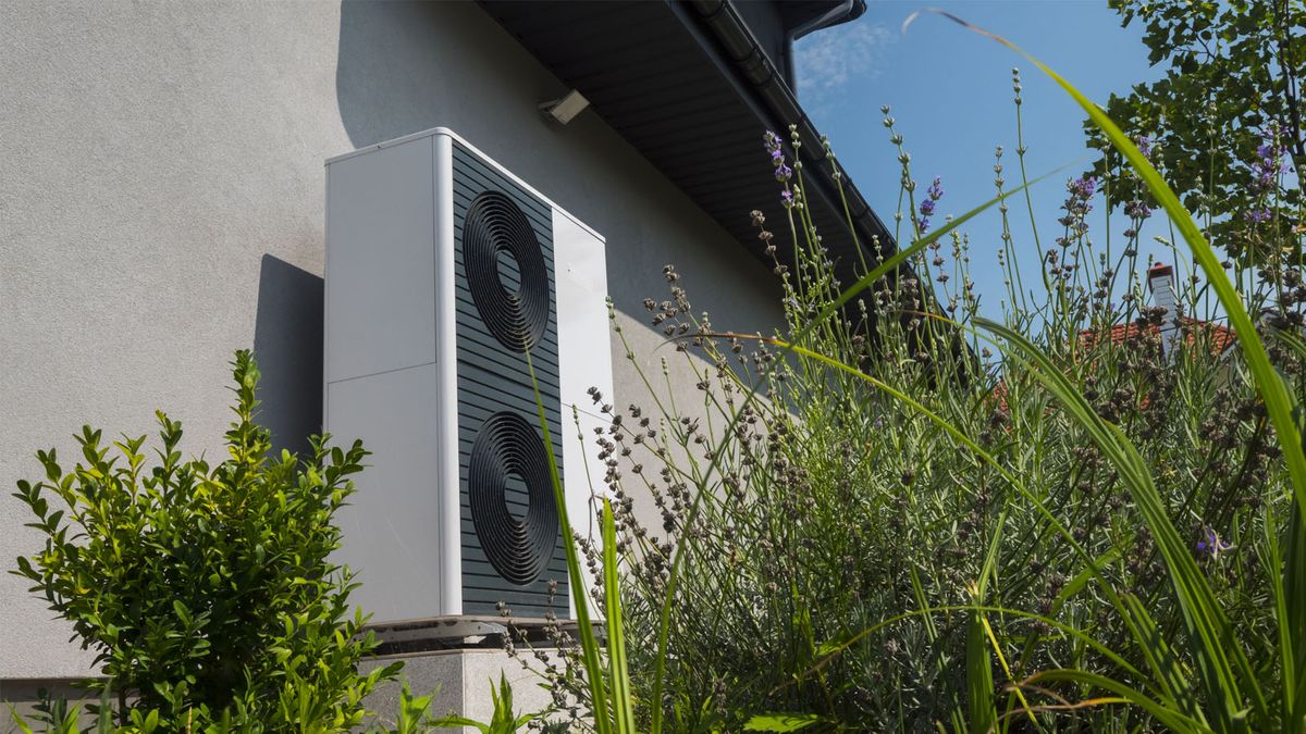 Outdoor AC unit mounted on the exterior wall of a home