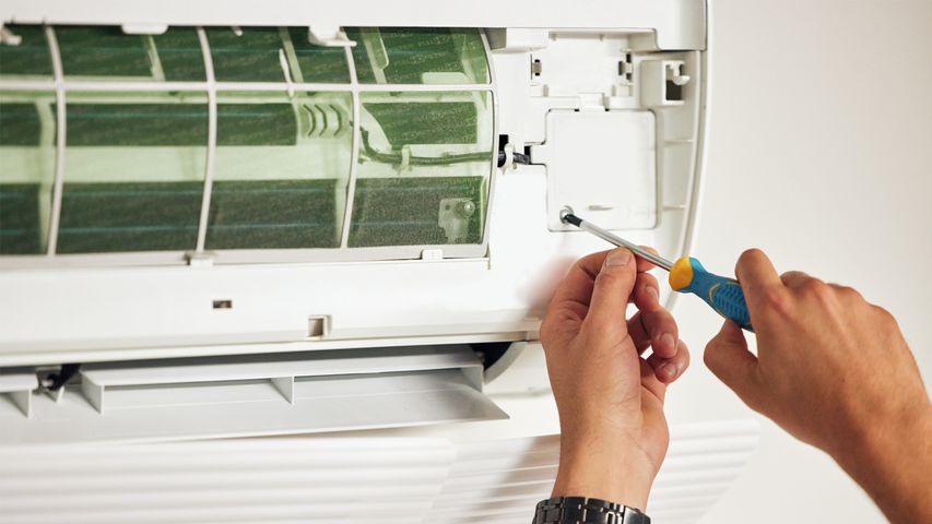 AC repair near me – professional HVAC repair technician fixing indoor air conditioner