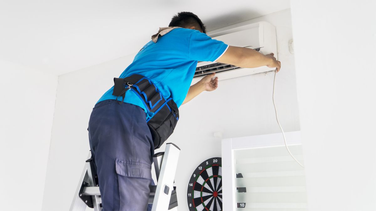 HVAC technician servicing a wall-mounted indoor AC unit in a Lauderhill, FL home