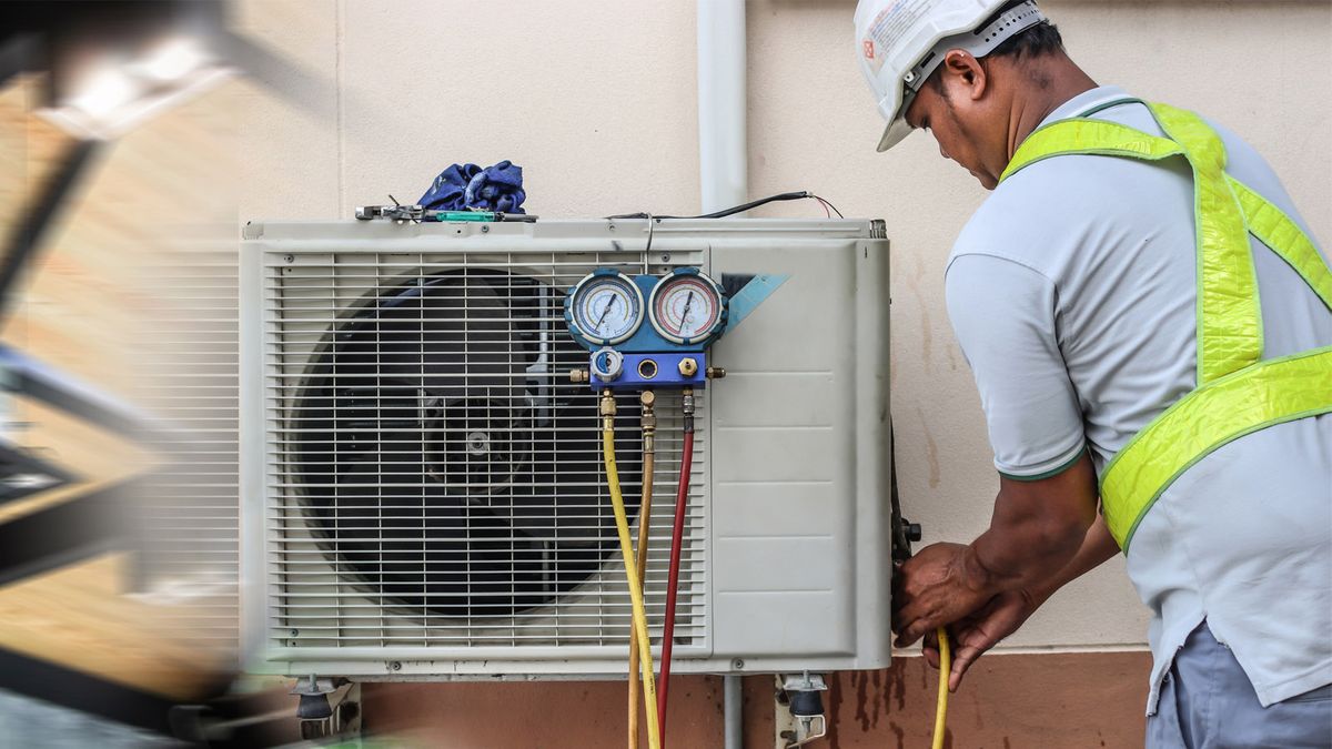 HVAC technician checking system pressures on an outdoor AC unit with manifold gauges during an AC repair visit in Davie, FL