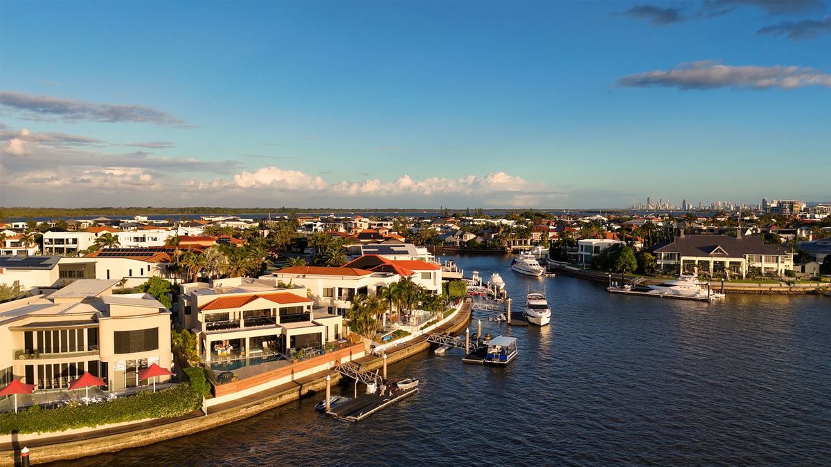 Aerial view of a South Florida residential neighborhood with tile-roof homes, palm trees and waterways