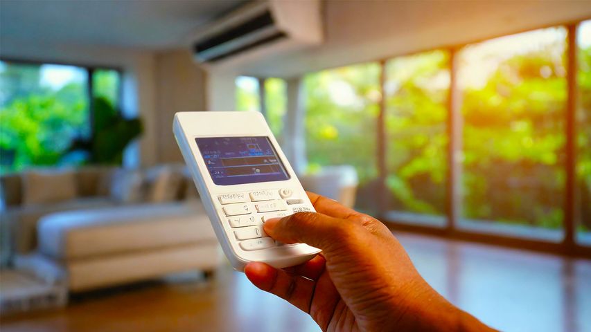 Homeowner adjusting AC settings with a remote in a Florida living room