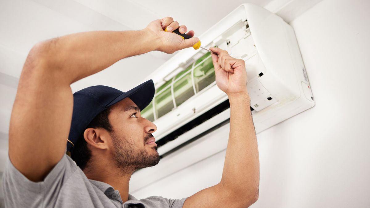 Aura America HVAC technician servicing a wall-mounted indoor AC unit in a Weston, FL home