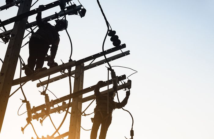 linemen silhouette on power poles