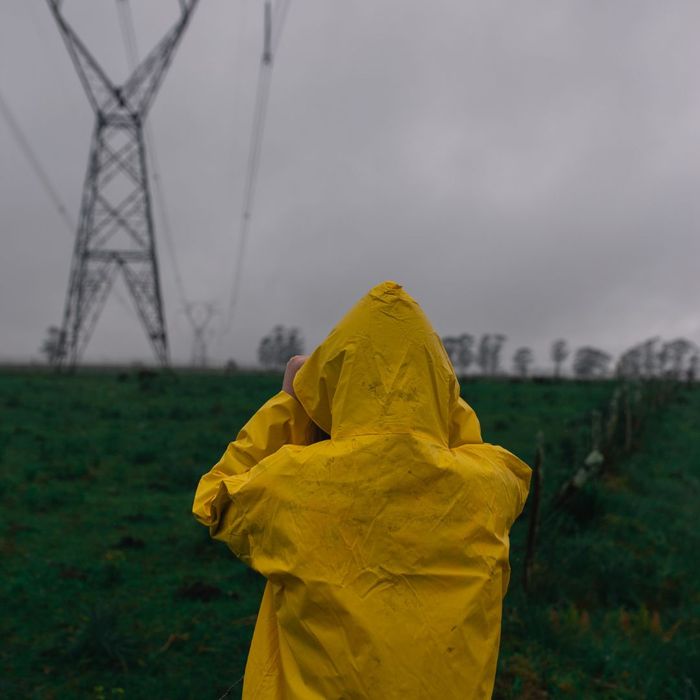 person in rain coat looking at powerlines