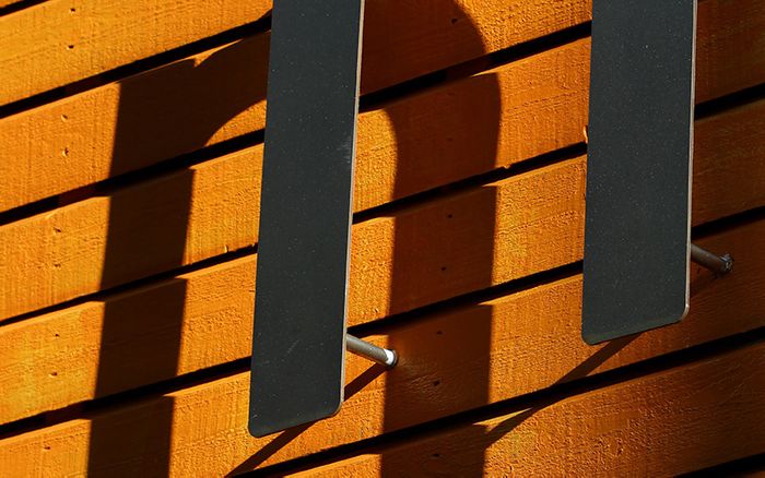 Metal letter N sign casting shadow on orange wall