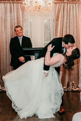 man dipping woman for their first kiss during wedding