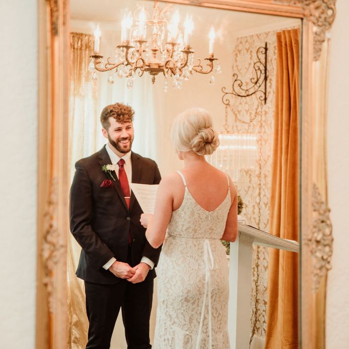 A bride and groom stand at the altar reflecting in a large ornate gold mirror during their Nashville ceremony.