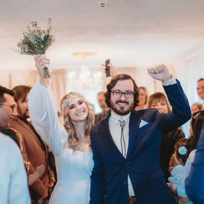Bride and groom raising their hands in celebration with wedding guests
