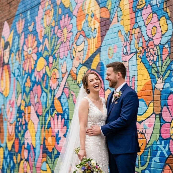 Joyful married couple taking wedding photos in front of a colorful street mural in downtown Nashville.