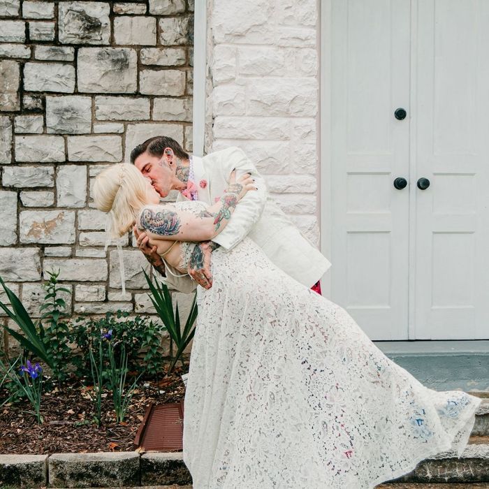 Bride dipping and kissing her groom outdoors in front of a white building Bride dipping and kissing her groom outdoors in front of a white building