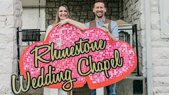 couple smiling in front of the rhinestone wedding chapel sign