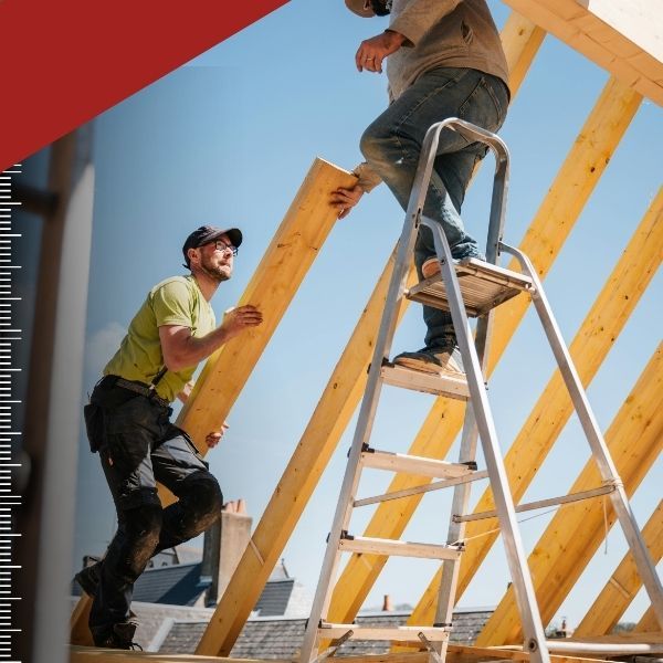 Two construction workers working on the wood frame of a home