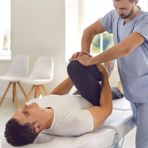 chiropractor bending client's leg up - piriformis stretch