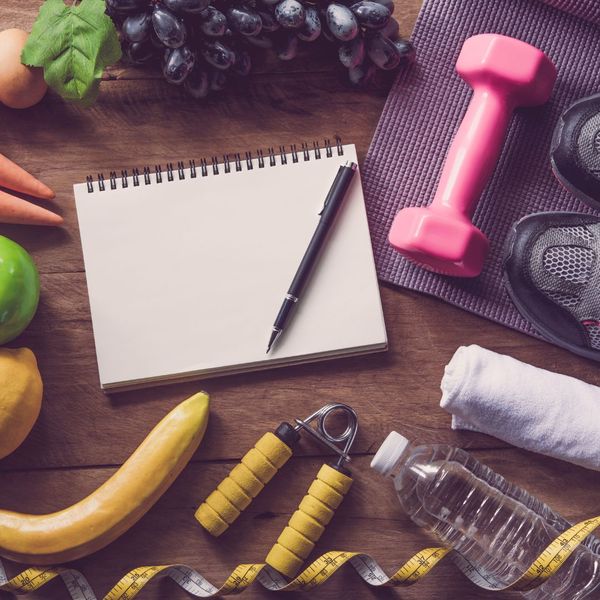 notebook surrounded by exercise equipment, accessories, and fruit