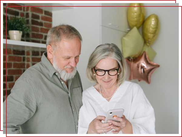 two seniors viewing something on a phone. 