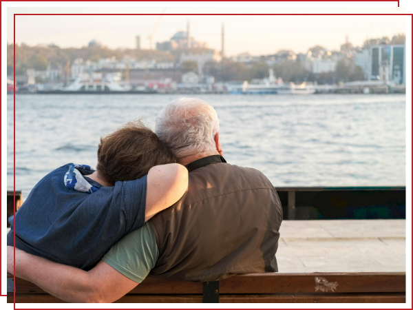 two elderly people hugging on a bench. 