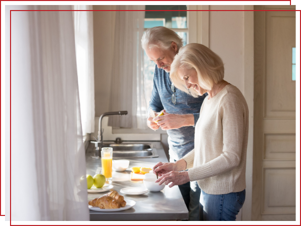 two seniors happily making food. 