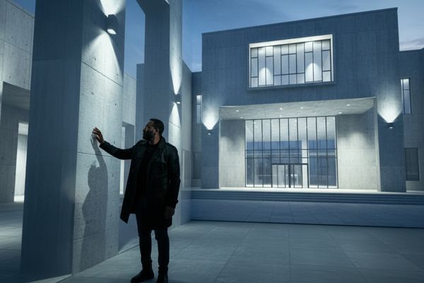 A man stands in an immersive projection of a photorealistic architectural rendering of a grand, contemporary museum facade, reaching out as if to touch a wall.