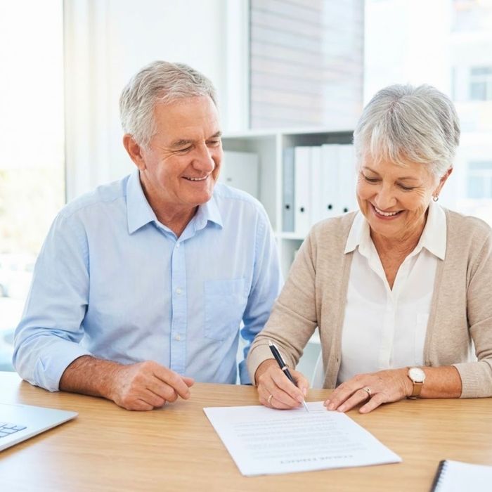 A couple smiling as they sign final documents.