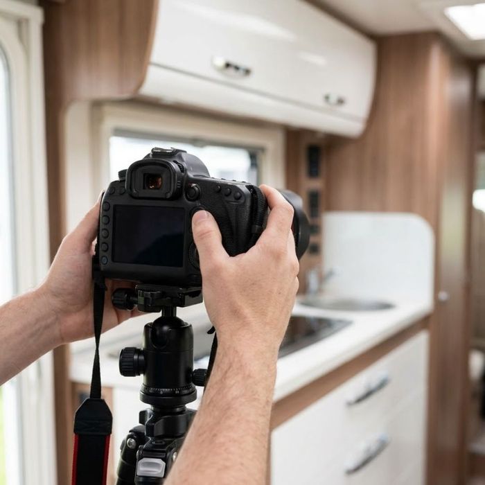 Hands adjusting a professional camera for motorhome photos.