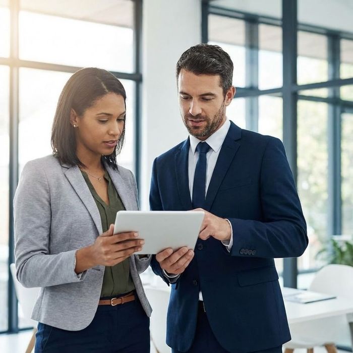 Two professionals review information on a tablet in a modern, secure office setting.