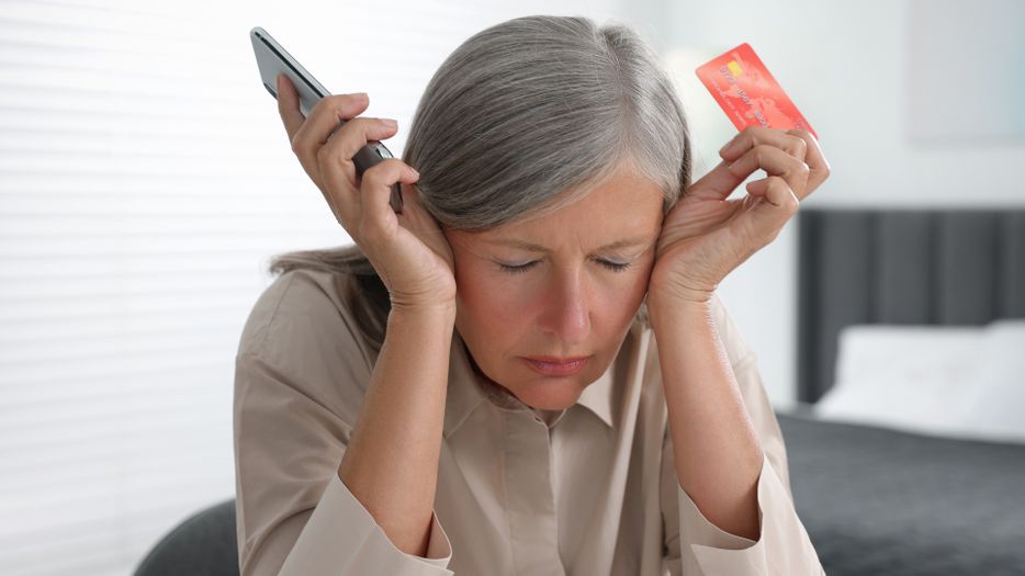 Frustrated woman holding phone and credit card