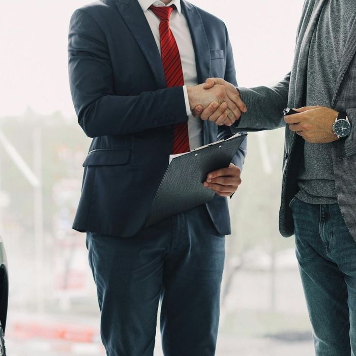 Two people shaking hands in a dealership.