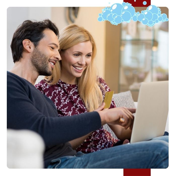 A couple smiles as they look at their bill on a laptop