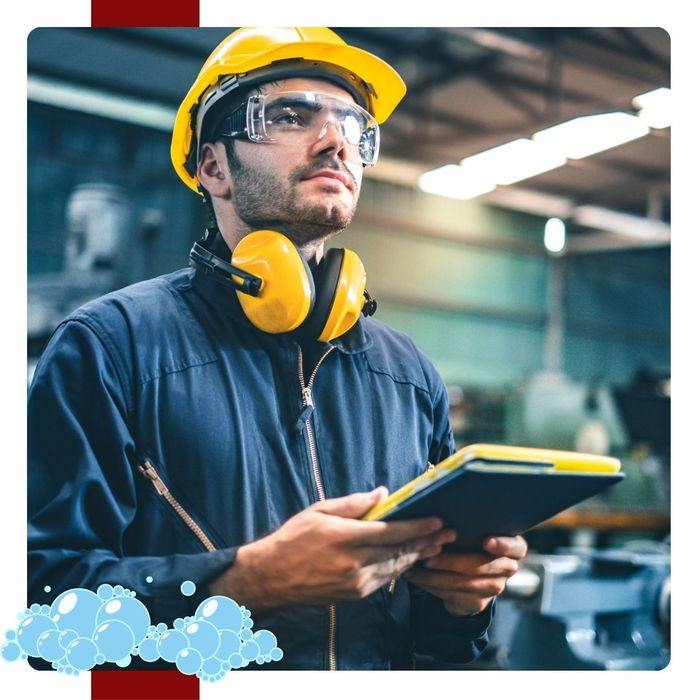 A contractor in safety gear standing in an industrial workplace.