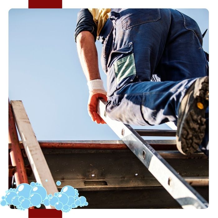 A roofer stepping off a ladder onto a roof