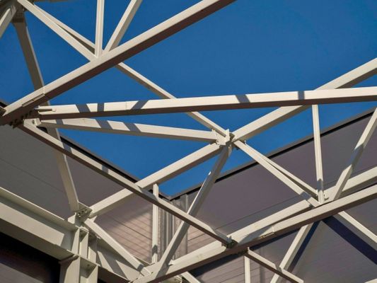 White steel trusses and framework of a commercial building against blue sky