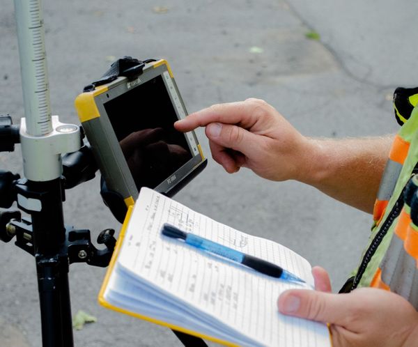 Hands operating a surveying tablet for environmental engineering land assessment