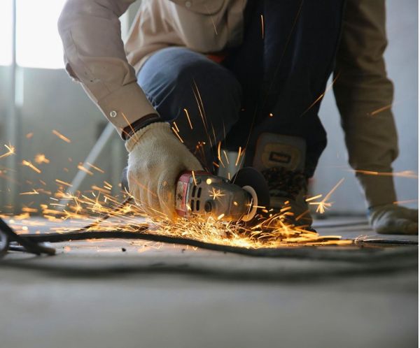 Construction worker using an angle grinder to cut metal, creating sparks