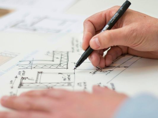 Hand drawing on architectural blueprints for construction planning