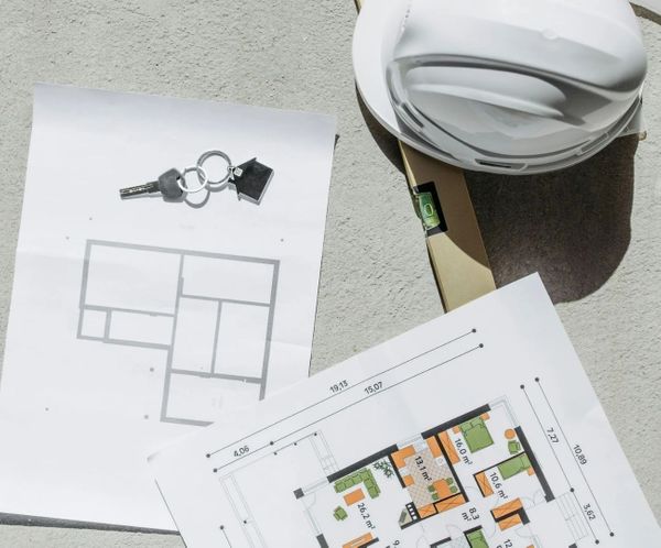 Construction plans, hard hat, and house keys on a blueprint