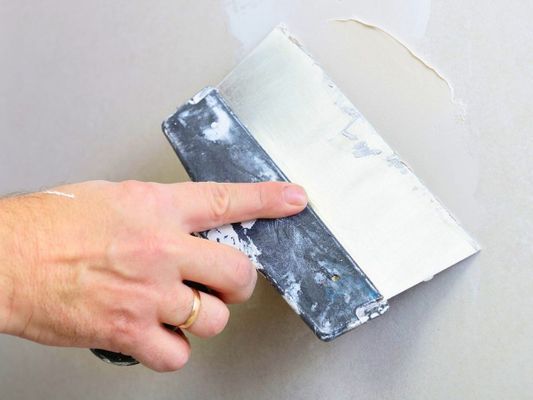 Hand applying spackle to a wall during drywall finishing